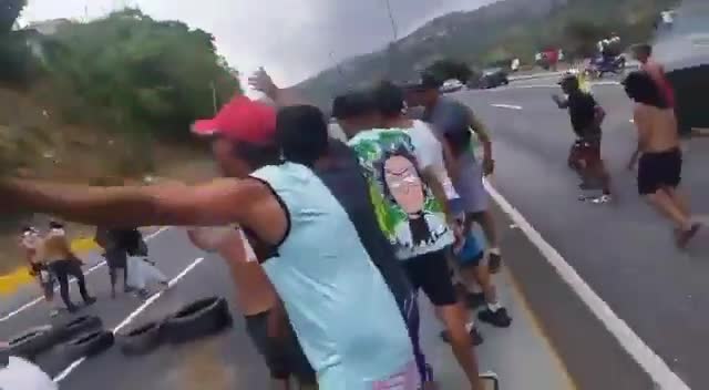 Des officiers de la Garde nationale (GNB) regardent les manifestants allumer des pneus en feu sur l'autoroute Caracas - La Guaira