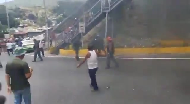 Angehörige der Nationalgarde (GNB) beobachten, wie Demonstranten auf der Autobahn Caracas – La Guaira Reifen anzünden.