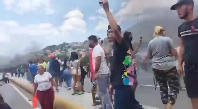 Des officiers de la Garde nationale (GNB) regardent les manifestants allumer des pneus en feu sur l'autoroute Caracas - La Guaira