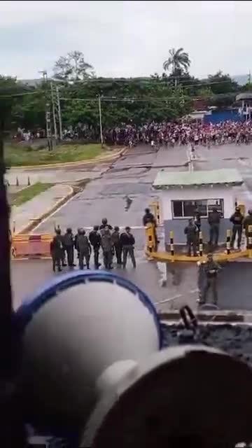 Große Menschenmenge von Demonstranten steht vor einem venezolanischen Luftwaffenstützpunkt dem Militär gegenüber