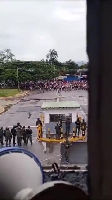 Une grande foule de manifestants face à face avec des militaires devant une base aérienne vénézuélienne