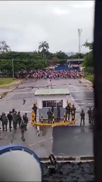 Une grande foule de manifestants face à face avec des militaires devant une base aérienne vénézuélienne