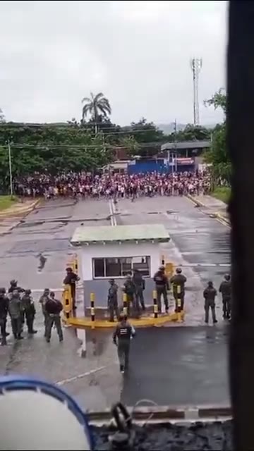 Une grande foule de manifestants face à face avec des militaires devant une base aérienne vénézuélienne