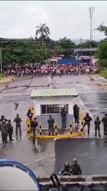 Große Menschenmenge von Demonstranten steht vor einem venezolanischen Luftwaffenstützpunkt dem Militär gegenüber