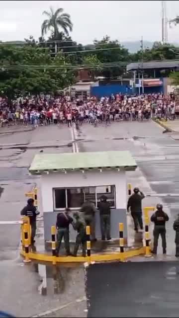 Große Menschenmenge von Demonstranten steht vor einem venezolanischen Luftwaffenstützpunkt dem Militär gegenüber