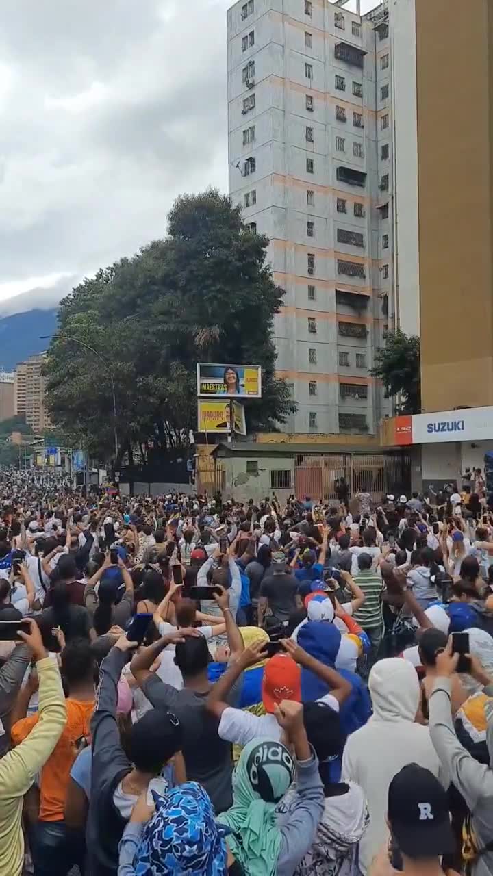 Demonstranten versuchen, in La California ein Propagandaschild von Maduro herunterzureißen.