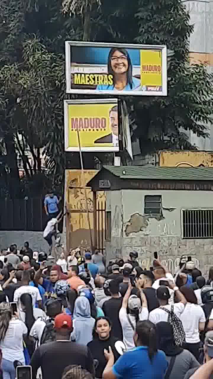 Demonstranten versuchen, in La California ein Propagandaschild von Maduro herunterzureißen.